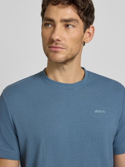Männermodel trägt Regular Fit T-Shirt aus Baumwoll-Mix Modell 'AUSTIN' von HUGO in Blau mit Waffel-Struktur, Nahaufnahme Oberkörper.
