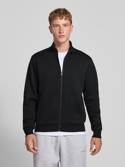 Männermodel trägt schwarze Regular Fit Sweatjacke mit Baumwoll-Anteil Modell 'Bradley' von JACK & JONES, Känguru-Tasche, Ganzkörperansicht von vorne. Herren Sweatjacke mit Stehkragen, Reißverschluss, Rückenlänge 68 cm, Ärmellänge 66 cm, Material-Mix.