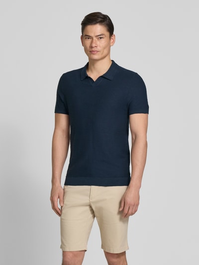 Mężczyzna nosi Regular Fit Poloshirt aus reiner Baumwolle von s.Oliver RED LABEL, kolor granatowy, krótki rękaw, materiał: dziana bawełniana, gładki wzór, krój regular fit, widok całej sylwetki z przodu.