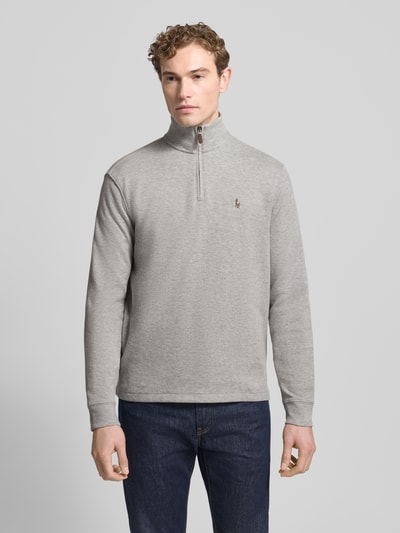 Männermodel trägt Sweatshirt mit Stehkragen von Polo Ralph Lauren, Reine Baumwolle, Regular-Fit, kurzer Reißverschluss, Label-Stitching, Grauton, glatte Textur, Rückenlänge 71 cm, Ärmellänge 65 cm, Ganzkörperansicht von vorne.