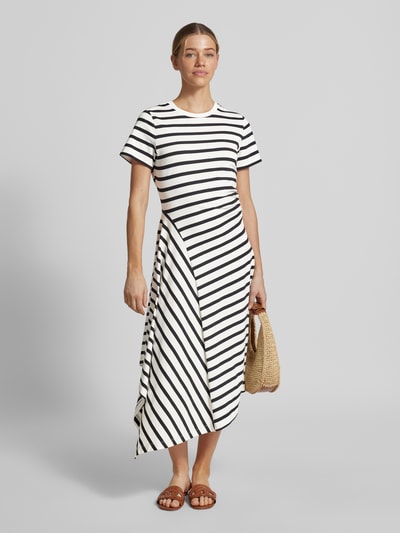 Frauenmodel trägt tailliertes Jersey-Kleid aus Baumwoll-Mix von s.Oliver RED LABEL mit schwarz-weißem Allover-Streifenmuster, asymmetrischem Saum und Kurzarm, Ganzkörperansicht von vorne.