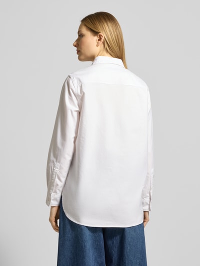 Vrouwenmodel draagt Relaxed Fit Hemdbluse aus reiner Baumwolle van Tommy Hilfiger, look: effen, pasvorm: relaxed fit, overhemdkraag, logodetail, achterpas, sluiting: knoopsluiting, mouwvorm: lange mouw, mouwboord: manchet, rompzoom: afgerond, materiaalverwerking: oxford, puur katoen. Ganzkörperaanzicht achteraan.