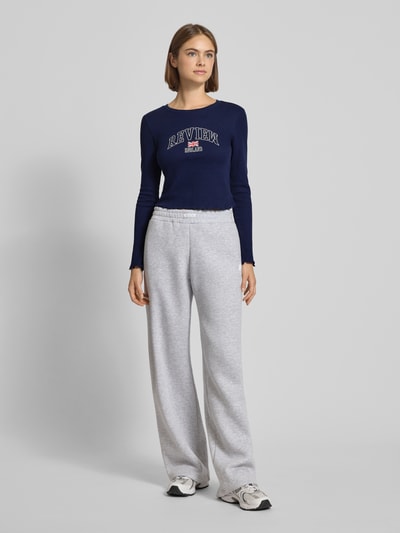 Frauenmodel trägt Longsleeve mit Muschelsaum von Review in Dunkelblau, Reine Baumwolle, eng anliegender Schnitt, Rundhalsausschnitt, Label-Print, Rückenlänge 41 cm bei Größe S, Ganzkörperansicht von vorne.
