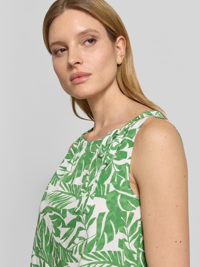 Frauenmodel trägt Blusenshirt mit Binde-Detail und Rundhalsausschnitt von More & More aus Reine Viskose, Gerade, grün-weißes Blattmuster, Nahaufnahme Oberkörper.