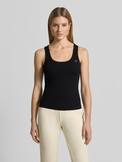 Frauenmodel trägt Slim Fit Top aus Viskose-Mix Modell 'Colette' von Guess Activewear, schwarz, Logo-Applikation, Ganzkörperansicht von vorne.