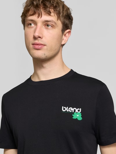 Männermodel trägt Regular Fit T-Shirt mit Logo-Print Modell 'Kenan' von Blend aus reiner Baumwolle, schwarze Farbe, Nahaufnahme Oberkörper.