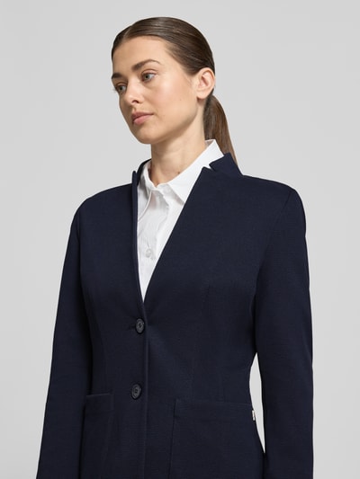 Vrouwenmodel draagt Blazer mit Reverskragen und Eingrifftaschen van WHITE LABEL in donkerblauw, getailleerd, met knoopsluiting en opgestikte steekzakken, katoenmix met stretch, detailopname bovenlichaam.