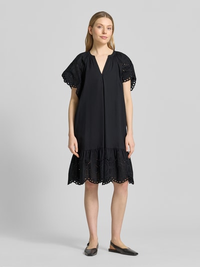 Modelka nosi Relaxed Fit Minikleid mit floraler Lochstickerei od Christian Berg Woman Selection, czarna bawełna, tunikowy dekolt, krótkie rękawy, Szerokość w rozmiarze 36: 34 cm, długość tyłu: 74 cm, długość rękawa: 26 cm, przód, widok całej sylwetki.