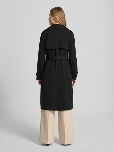 Modelka nosi czarny trencz dwurzędowy z wiązanym paskiem od MICHAEL Michael Kors, krój regular fit, widok całej sylwetki z tyłu. Długość tyłu w rozmiarze S: 47 cm, szerokość ramion w rozmiarze S: 40 cm, szerokość w klatce piersiowej w rozmiarze S: 50 cm, długość rękawów w rozmiarze S: 63 cm.