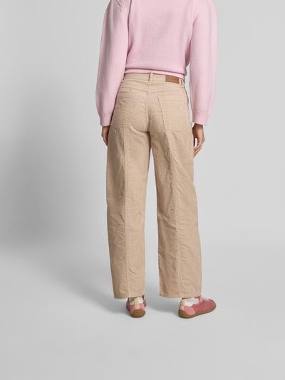 Frauenmodel trägt Straight Fit Cordhose mit Logo-Patch von BAUM & PFERDGARTEN in Beige, sichtbare Taschenstruktur, reine Baumwolle, Ganzkörperansicht Rückansicht.