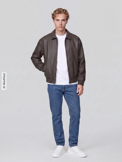 Männermodel trägt braune Regular Fit Kunstlederjacke Modell 'REX' von ONLY, blaue Jeans, weiße Sneaker, Herren Leder- / Kunstlederjacke von ONLY & SONS, Ganzkörperansicht von vorne, KI-modifiziertes Bild