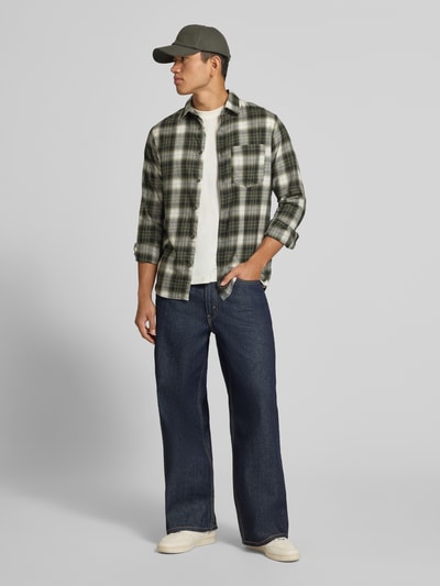 Männermodel trägt Slim Fit Freizeithemd aus reiner Baumwolle Modell 'James' von JACK & JONES in grün kariert, mit Brusttasche und Kentkragen, Ganzkörperansicht von vorne.