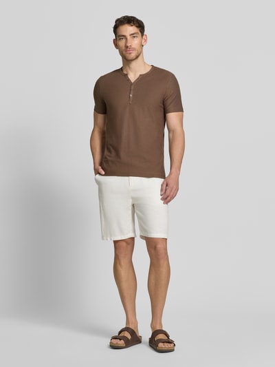 Mężczyznęmodel nosi T-Shirt mit V-Ausschnitt und Knopfleiste von MCNEAL z bawełny, krój regular fit, długość tyłu w rozmiarze M: 68 cm, brązowy, gładka faktura. Ganzkörperansicht von vorne.