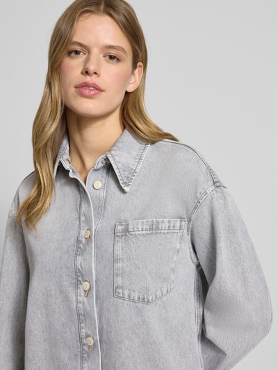 Frauenmodel trägt Loose Fit Jeanskleid aus reiner Baumwolle von Marc O'Polo Denim in grauer Denim-Optik mit Brusttasche, Nahaufnahme Oberkörper.