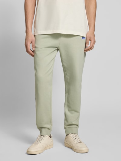 Männermodel trägt Relaxed Fit Sweatpants aus reiner Baumwolle Modell 'NAPIN' von Hugo Blue in Optik: Unifarben, Nahaufnahme Unterkörper. Passform: Relaxed-Fit, Label-Patch am Bund, Tunnelzug-Verschluss, elastischer Bundabschluss, gerippter Beinabschluss, seitliche Eingrifftaschen, Materialverarbeitung: Sweat.