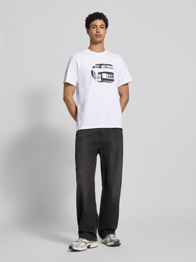 Männermodel trägt Regular Fit T-Shirt mit Logo-Print Modell 'icon' von G-Star Raw aus reiner Baumwolle, weiß, Ganzkörperansicht von vorne.