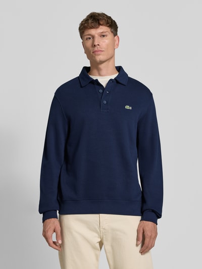 Männermodel trägt Regular Fit Sweatshirt aus reiner Baumwolle von Lacoste in Dunkelblau mit Polo-Kragen, Herren Sweatshirt, Ganzkörperansicht von vorne.