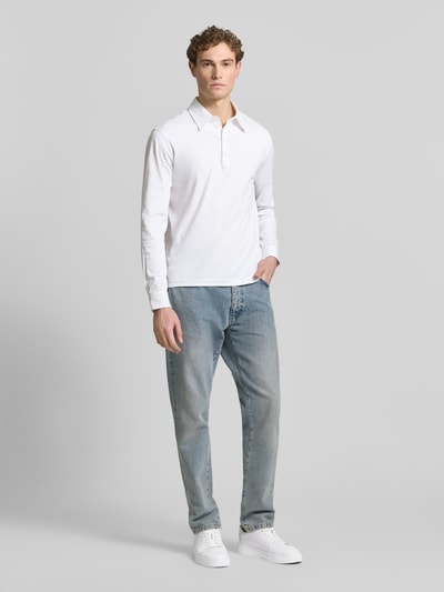 Männermodel trägt Regular Fit Poloshirt aus Baumwolle Modell 'Tanner' von Tiger of Sweden in Weiß, langärmlig, Ganzkörperansicht von vorne.