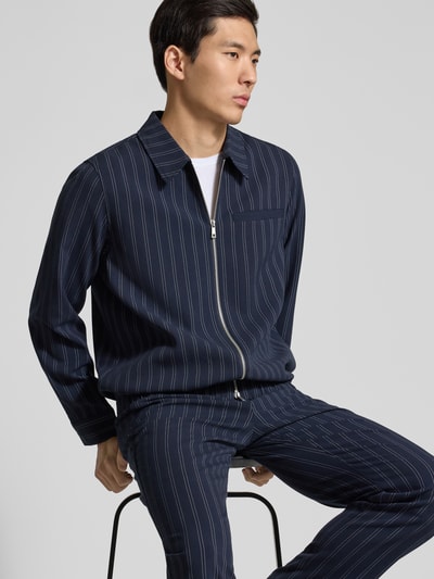 Männermodel trägt Modern Fit Hemdjacke mit Zweiwege-Reißverschluss von Lindbergh, dunkelblau gestreift, Material-Mix, Nahaufnahme Oberkörper.