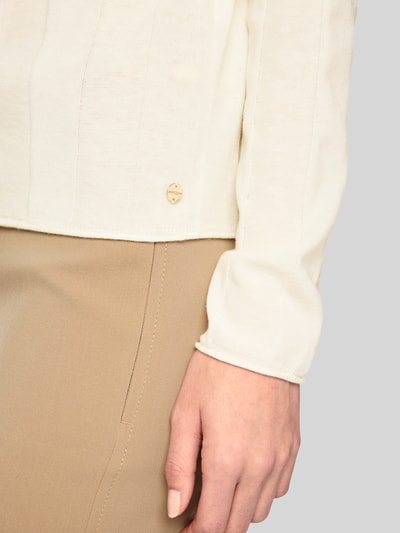 Frauenmodel trägt Strickpullover aus Schurwolle-Mix mit Stehkragen von Marc Cain in Creme, weiche Textur, Nahaufnahme Oberkörper, Damen Strickpullover, Slim Fit, Label-Detail, Kaschmir-Anteil.