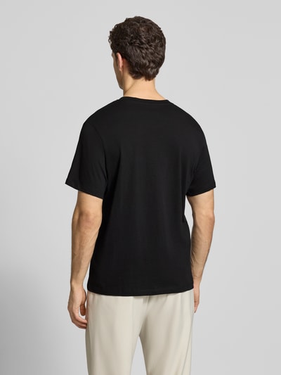 Männermodel trägt Regular Fit T-Shirt aus reiner Baumwolle Modell 'HASPEN' von SELECTED HOMME in Schwarz, Ganzkörperansicht Rückansicht.