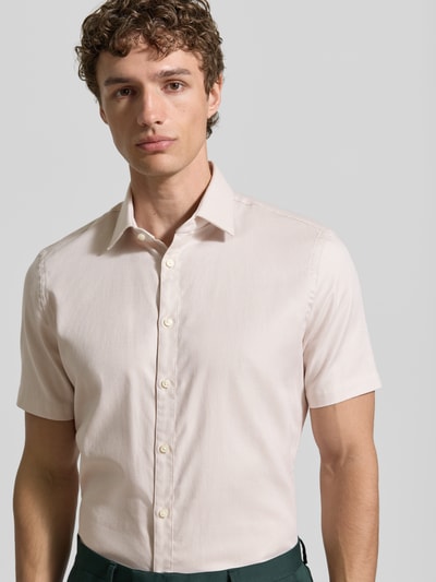Männermodel trägt Slim Fit Business-Hemd aus Baumwolle mit Kentkragen von Jake*s in Hellbeige, glatte Textur, Nahaufnahme Oberkörper. Kontext: Kurze Ärmel, Knopfleiste, klassische Business-Optik, Rückenlänge 78 cm, Schulterbreite 47 cm, Ärmellänge 24 cm.