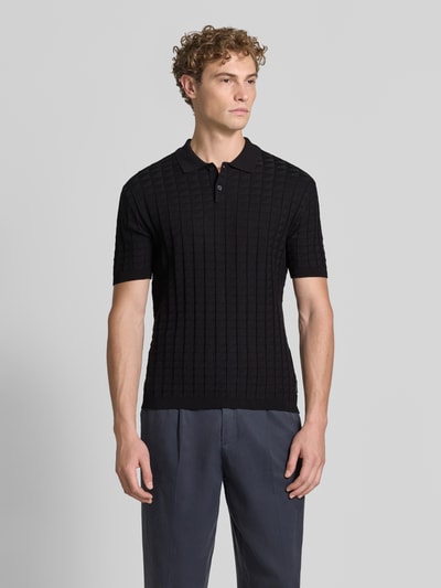 Männermodel trägt Regular Fit Poloshirt aus Viskose-Mix Modell 'Maglia' von Armani Exchange in Schwarz, Stepp- und Strick-Optik, Ganzkörperansicht von vorne.