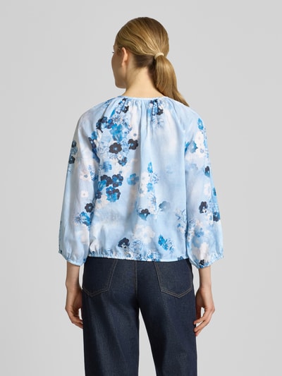 Frauenmodel trägt Regular Fit Bluse im Allover-Look mit Schlüsselloch-Ausschnitt von monari, Baumwoll-Viskose-Mix, Rückenlänge 53 cm, Ärmellänge 41 cm, Bluse in Blau mit floralem Muster, lockere Passform, Ganzkörperansicht Rückansicht.