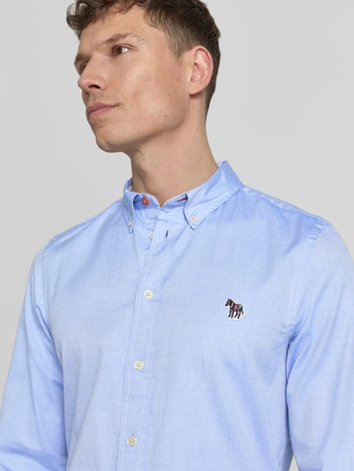 Männermodel trägt Tailored Fit Freizeithemd mit Button-Down-Kragen von PAUL SMITH aus reiner Baumwolle, dezentes Stitching, hellblau, Nahaufnahme Oberkörper.