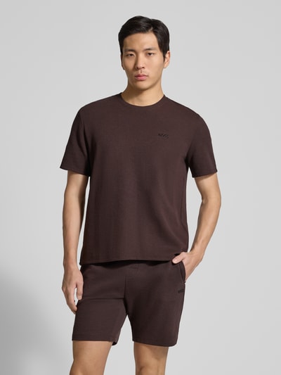 Männermodel trägt Regular Fit Pyjama-Oberteil aus Baumwoll-Mix Modell 'WAFFLE' von BOSS in Braun, strukturierte Piqué-Optik, Label Stitching, Ganzkörperansicht von vorne.