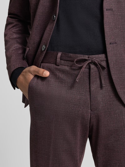 Männermodel trägt Straight fit stoffen broek met tunnelkoord Model 'Sparta' van Zuitable in bordeaux, bandplooien, steek- en achterzakken, detailaufnahme. Heren stoffen broek, bandwijdte maat 50: 43 cm, binnenbeenlengte maat 50: 82 cm.