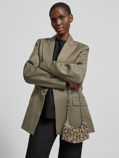 Frauenmodel trägt Shoulder Bag in Ketten-Optik von Rabanne, gold-silber, strukturierte Oberfläche, Schulterriemen, Logo-Applikation, Nahaufnahme Oberkörper.