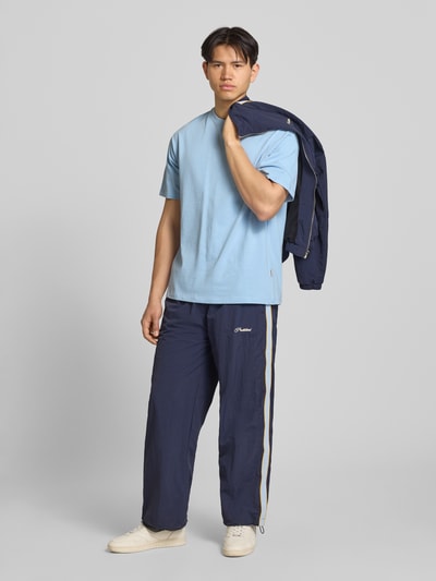 Männermodel trägt Oversized T-Shirt Modell 'FISHER' von Blend in Hellblau, reine Baumwolle, Rundhalsausschnitt, Ganzkörperansicht von vorne.