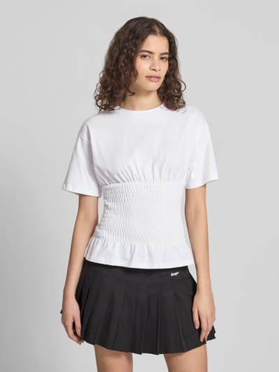 Modelka kobieca ma na sobie tailliertes T-Shirt mit Rundhalsausschnitt Modell 'EVELYN' od JJXX, czysta bawełna, krój slim fit, smokowane detale, kolor biały, przód i dół z fakturą, długość tyłu w rozmiarze S: 53 cm, widok na cały przód sylwetki.
