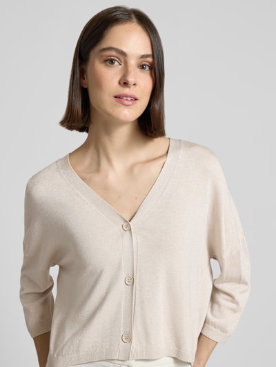 Frauenmodel trägt Schimmernde Strickjacke mit 3/4-Arm von comma in Beige, V-Ausschnitt, Knopfleiste, Relaxed Fit, Nahaufnahme Oberkörper.