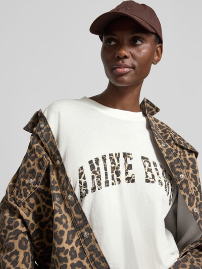 Frauenmodel trägt Oversized T-Shirt aus reiner Baumwolle von Anine Bing mit Label-Print und Rundhalsausschnitt im Halbarm, Nahaufnahme Oberkörper
