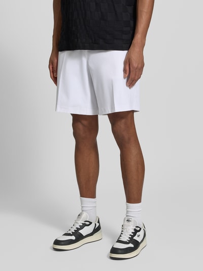 Männermodel trägt Relaxed Fit Bermudas mit Label-Schriftzug Modell 'SPIRIT70' von BOSS Green X PORSCHE, unifarbenes Weiß, Nahaufnahme Unterkörper.