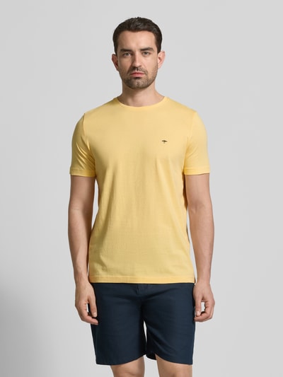 Męski model nosi T-Shirt mit Rundhalsausschnitt und Label-Stitching od Fynch-Hatton, czysta bawełna, krój regular fit, żółty kolor, długość tyłu w rozmiarze M: 71 cm, widok całej sylwetki z przodu.