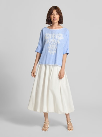 Frauenmodel trägt Blusenshirt mit Leinen-Anteil und Motiv-Stitching von Christian Berg Woman, Mieszanka wiskozy i lnu, krój loose fit, dekolt w łódkę z kontrastową lamówką, wyhaftowany motyw, Długość tyłu w rozmiarze 36: 55 cm, Długość rękawów w rozmiarze 36: 34 cm, jasnoniebieski i biały, gładka tekstura, Ganzkörperansicht von vorne