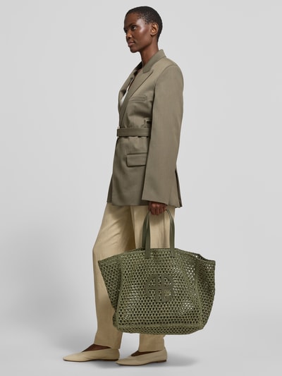 Vrouwenmodel draagt Tote Bag met logo-applicatie van Anine Bing, zuiver cellulose, semi-transparante look, hoofdvak, draagriem; zijaanzicht, volledige lichaamsopname.