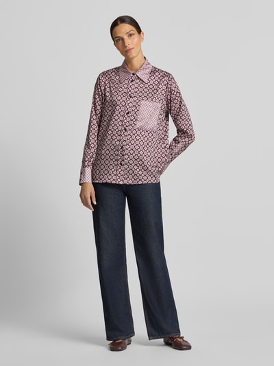 Frauenmodel trägt Relaxed Fit Hemdbluse Modell 'CAMICIA' von Liu Jo White aus satinartigem Stoff mit Muster, Hemdblusenkragen, Brusttasche, langen Ärmeln, dunkle Hose, Ganzkörperansicht von vorne.