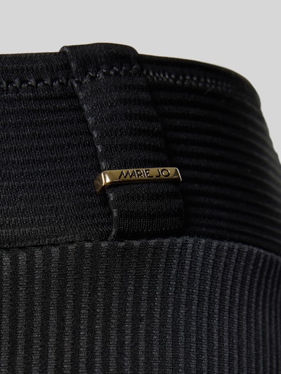 Frauenmodel trägt Bikini-Slip mit Label-Detail von Marie Jo in Schwarz, Material-Mix mit Stretch, Nahaufnahme Hüfte, elastischer Bund, strukturiertes Gewebe.