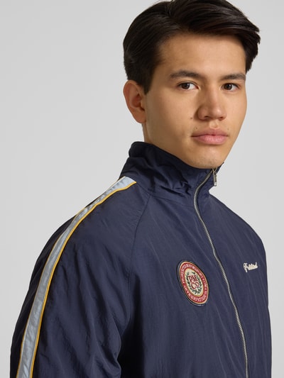 Männermodel trägt Trackjacket mit Label-Stitching Modell 'Slipstream' von PROHIBITED, entspannter Schnitt, Nahaufnahme Oberkörper.
