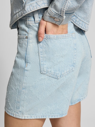 Frauenmodel trägt Jeansshorts im 5-Pocket-Design Modell '90S' von Calvin Klein Jeans in hellem Blau, Reine Baumwolle, Wide-Fit, Label-Detail, Detailaufnahme Rückansicht.