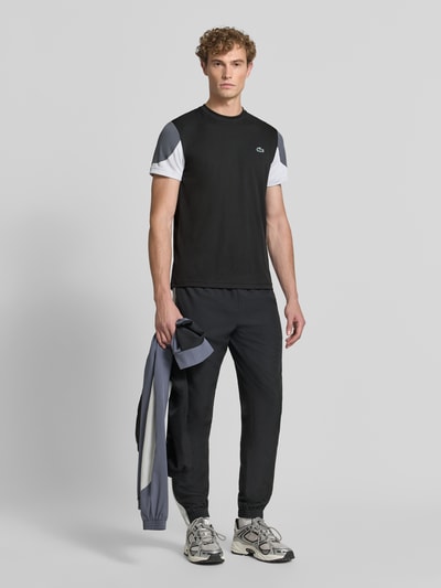 Männermodel trägt Regular Fit Sport-T-Shirt im Colorblock-Design von Lacoste, Schwarz mit Weiß und Grau, Herren Sport-T-Shirt, Ganzkörperansicht von vorne.