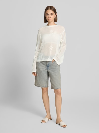 Frauenmodel trägt sweter z dzianiny z bawełny OH APRIL Model 'Ronja', krój regular fit, okrągły dekolt, wyhaftowane logo, Długość tyłu w rozmiarze S: 53 cm, Długość rękawów w rozmiarze S: 67 cm, jasne kolory, siateczkowa faktura, Ganzkörperansicht von vorne.