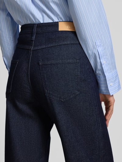 Frauenmodel trägt Wide Leg Jeans aus Viskose-Baumwoll-Mix Modell 'SURI' von s.Oliver BLACK LABEL, dunkelblauer Denim, Nahaufnahme Rückansicht.