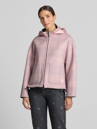 Frauenmodel trägt Regular Fit Jacke mit Kapuze von Marc Cain in zartem Rosa mit Karomuster und Zweiwege-Reißverschluss, Nahaufnahme Oberkörper. Rückenlänge 65 cm, Schulterbreite 59 cm, Brustweite 63 cm, Ärmellänge 50 cm.
