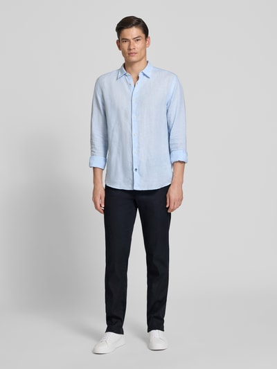 Męski model nosi Regular Fit Stoffhose aus Baumwoll-Leinen-Mix Modell 'CADIZ' od Brax, jednokolorowe, 5 kieszeni, label patch, bawełna z lnem, krój regular fit, z przodu widok całopostaciowy.