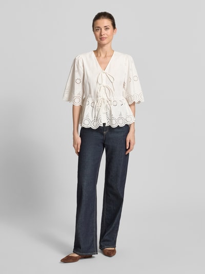 Vrouwenmodel draagt witte dames blouse van YAS met ajourwerk, regular fit, model 'Cornelia', V-hals, halflange mouwen, sierstrik, ruglengte maat 36: 56 cm, mouwlengte maat 36: 37 cm, voorkant geheel in beeld.